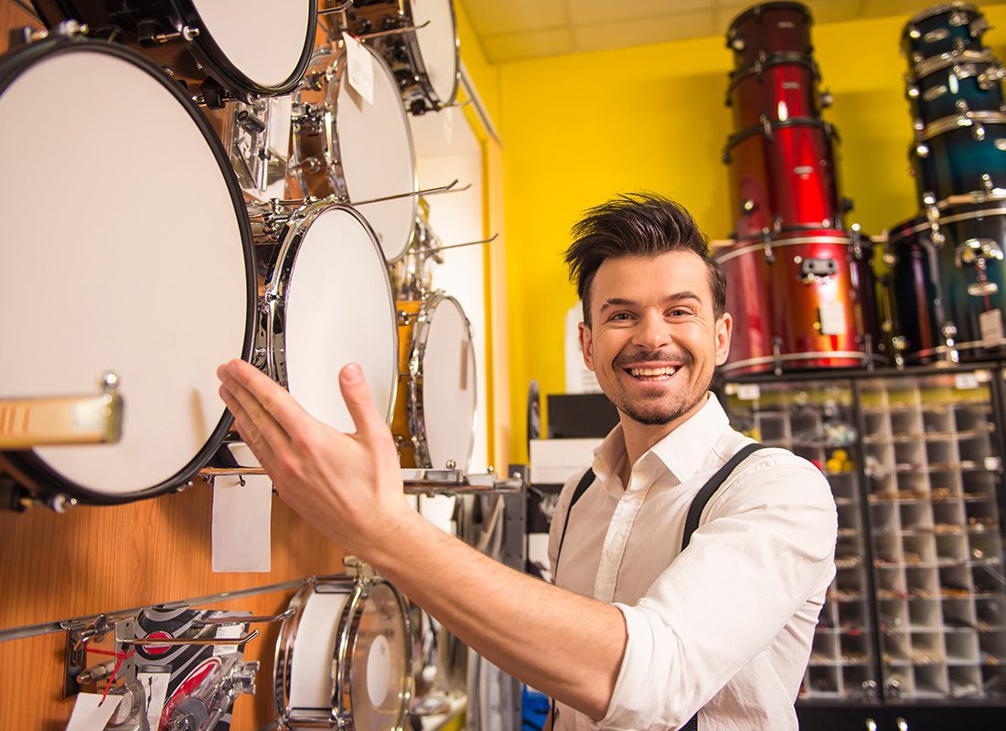 Business Insurance - Friendly Business Owner Showcasing Musical Instruments