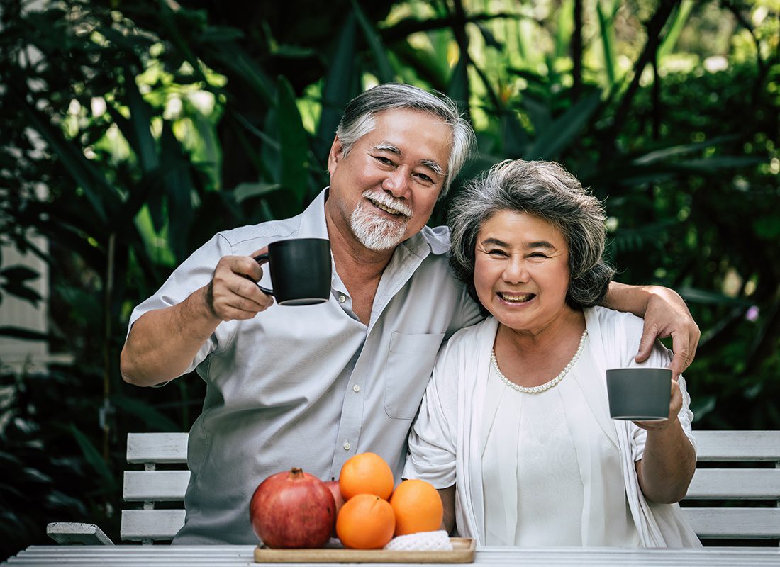 Medicare - Elderly Couple Sitting Outside Having Fruits and Tea