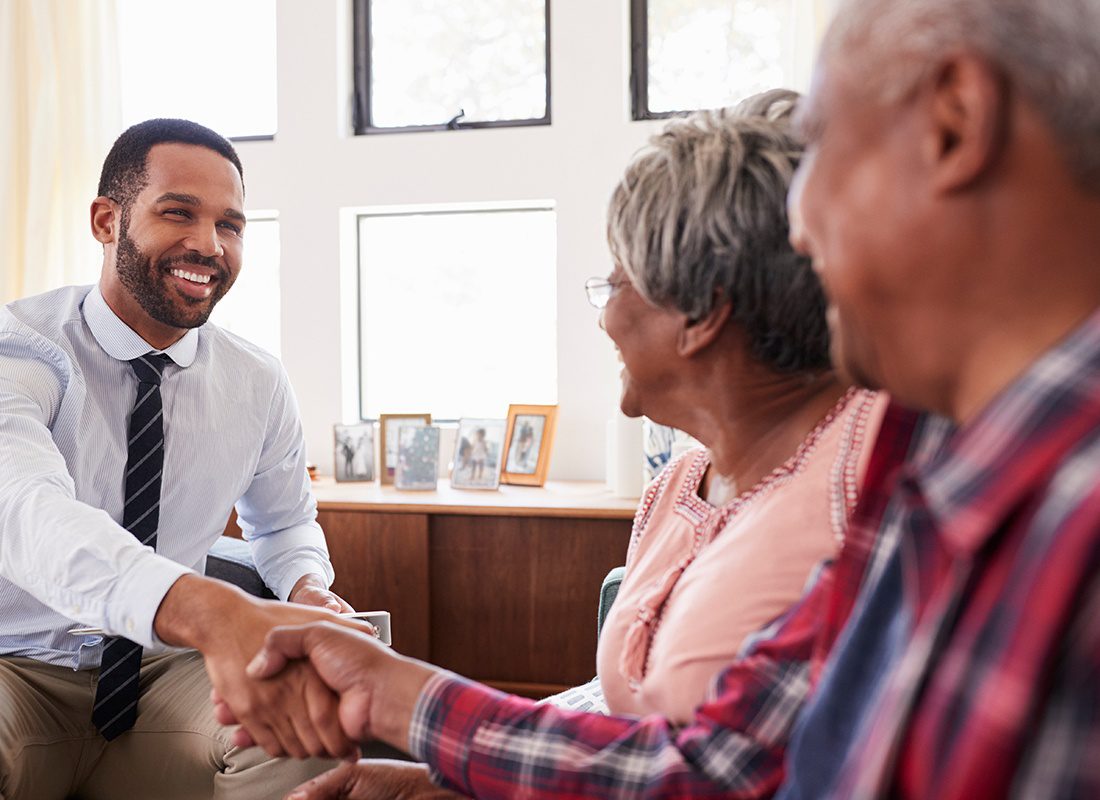 Personal Insurance - Agent Sitting With Older Couple Shaking Hands
